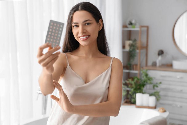 Jovem com pílulas contraceptivas no banheiro - Foto, Imagem