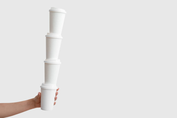 Mano femenina con pila de vasos de papel para llevar sobre fondo blanco - Foto, imagen