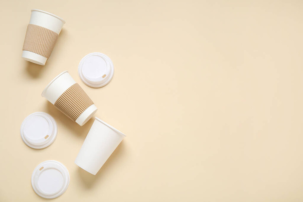 Tazas de papel para llevar con tapas sobre fondo beige - Foto, Imagen