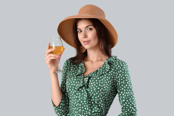 Mooie jonge vrouw met glas wijn op lichte achtergrond - Foto, afbeelding