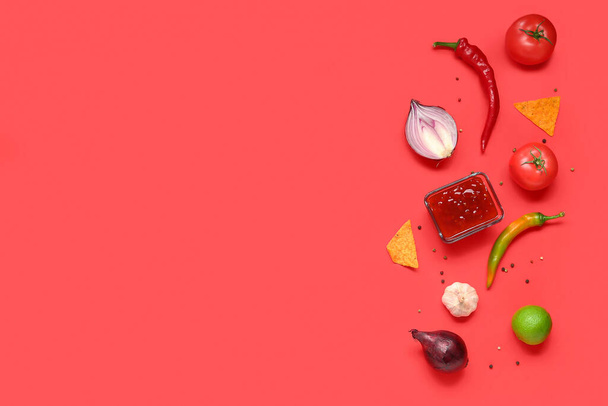 Bowl with tasty salsa sauce, nachos and ingredients on red background - Photo, Image