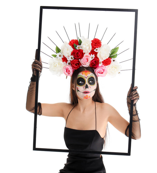 Young woman with painted skull and frame on white background. Mexico's Day of the Dead (El Dia de Muertos) celebration - Photo, Image