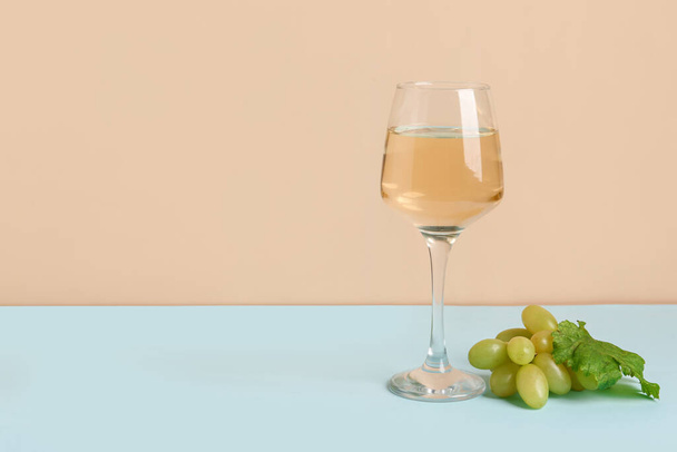 色の背景にワインのブドウとグラス - 写真・画像