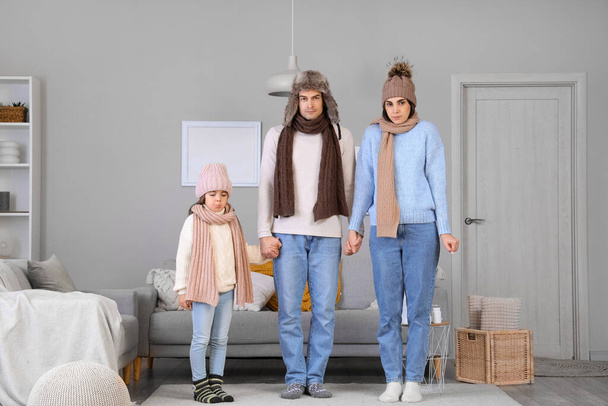 Bevroren familie in warme kleren thuis met gebrek aan verwarming - Foto, afbeelding