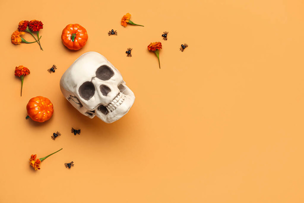 Human skull with marigold flowers, pumpkins and spiders on orange background - Photo, Image