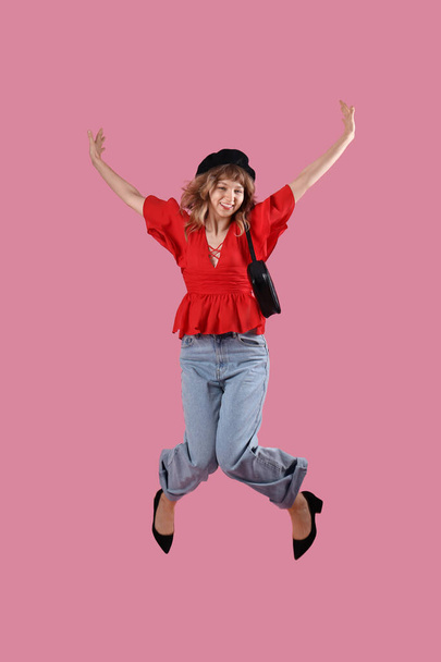 Jumping young woman in autumn clothes on pink background - Photo, Image