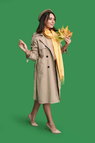 Belle jeune femme avec des feuilles d'automne sur fond vert - Photo, image