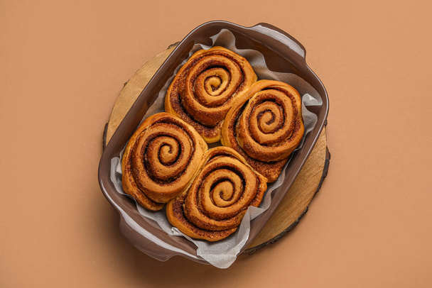 Baking dish of tasty cinnamon rolls on brown background - Photo, Image