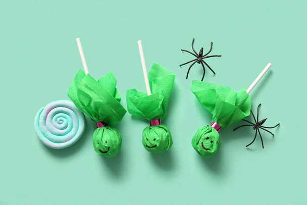Sweet lollipops with spiders and candy for Halloween party on turquoise background - Photo, Image