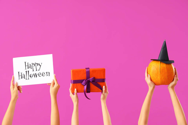 Mujeres con regalo de Halloween, tarjeta y calabaza sobre fondo púrpura - Foto, Imagen