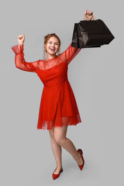 Όμορφη νεαρή γυναίκα με τσάντες για ψώνια σε γκρι φόντο. Μαύρη Παρασκευή πώληση - Φωτογραφία, εικόνα
