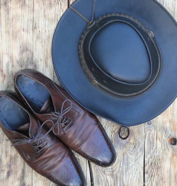 chapeau de cow-boy et chaussures en cuir sur un vieux fond en bois - Photo, image