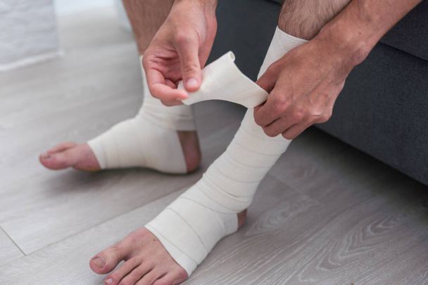 mężczyzna za pomocą umieścić na elastyczny bandaż z nogami mających ból nóg. - Zdjęcie, obraz