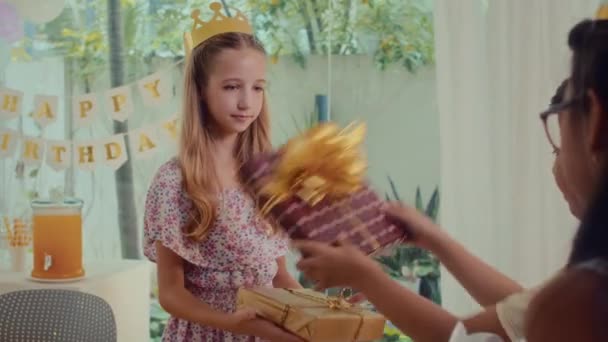 Πάνω από τον ώμο του άποψη των παιδιών δίνοντας δώρα γενεθλίων στο φίλο τους στο σπίτι κόμμα - Πλάνα, βίντεο