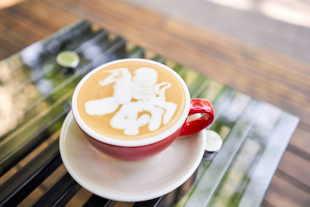 Bir adam kahve içiyor, elinde bir fincan sıcak Peanut latte tutuyor. Kahve dükkanının ortak çalışma alanındaki masa. Güneşli bir günde verandada bir fincan kahve. Kafede kahve molası. Yakın plan. - Fotoğraf, Görsel