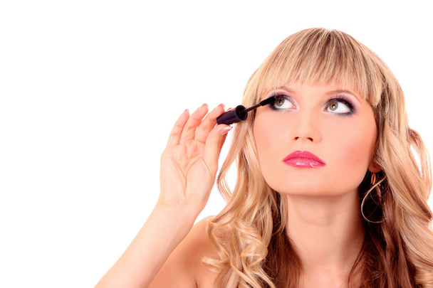 Beautiful young blonde woman applying mascara on her eyelashes - Photo, image