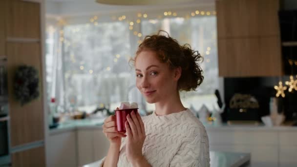 Egy vörös hajú nő portréja, kezében egy csésze forró csokoládéval és mályvacukorral. Lövés RED hélium kamerával 8K-ban.   - Felvétel, videó