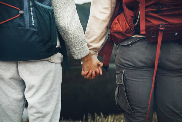 Couple, holding hands and backpack in nature for hiking, adventure or outdoor journey together. Rear view or closeup of hiker, people or backpacking in teamwork for trekking, motivation or support. - Photo, Image