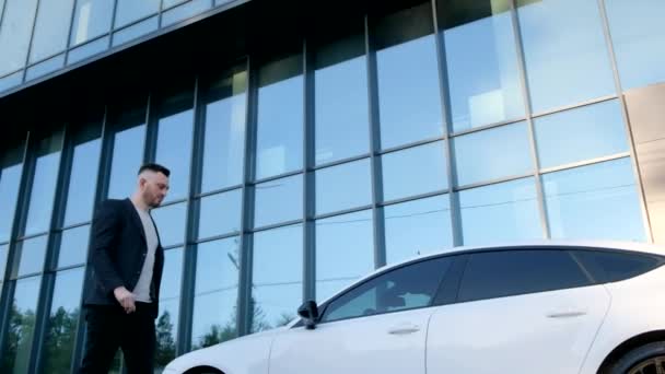De zakenman doet de deur open en stapt in de auto. Concept van succes en rijkdom. - Video