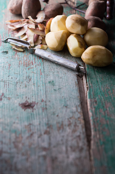 Peeled potatoes on aged wooden table - Photo, Image