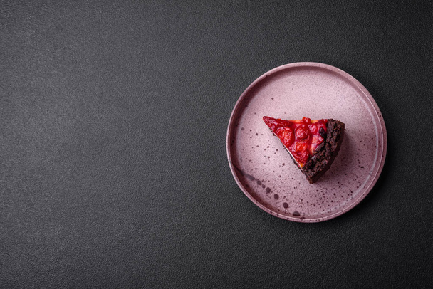 Hermosa rebanada sabrosa dulce de pastel de queso con cereza en un plato de cerámica sobre un fondo de hormigón oscuro - Foto, Imagen