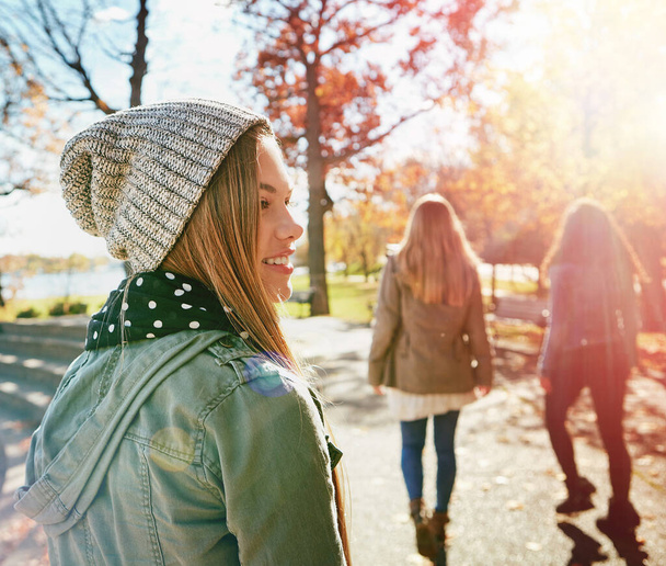 Tiener meisje in de natuur met vrienden, wandelen in het park met herfst en zon, wellness met geluk. Jeugd buiten, genieten van frisse lucht en hechting met een glimlach, lens opvlammen met avontuur of reizen. - Foto, afbeelding