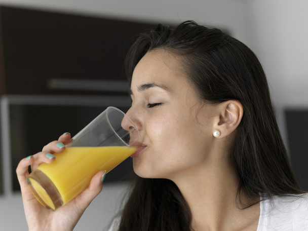 Woman drinking juice in her kitchen - Fotoğraf, Görsel