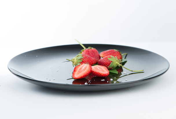 frische halbe Erdbeere auf schwarzem Teller und Reflex - Foto, Bild