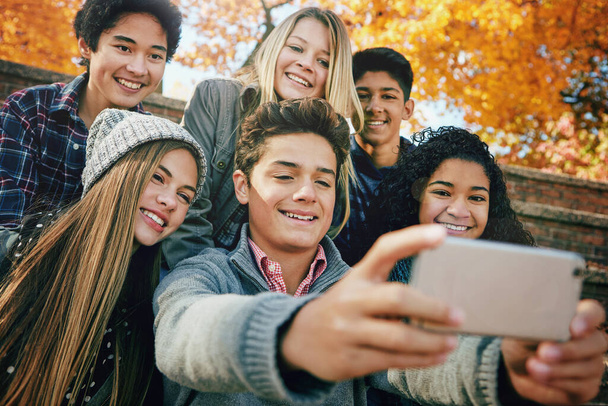 Selfie, hymy tai ystäviä puistossa sosiaalisen median, verkossa postitse tai profiilin kuva yhdessä syksyllä tai luonnossa. Tytöt, gen z pojat tai onnelliset ihmiset ottavat valokuvan hauskaa lomaa varten rentoutumaan. - Valokuva, kuva