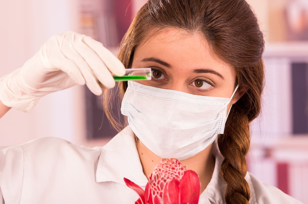 beautiful female biologist experimenting with red flower - Zdjęcie, obraz