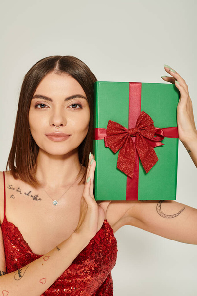 attractive woman with pierced nose and tattoos showing present at camera, holiday gifts concept - Photo, Image