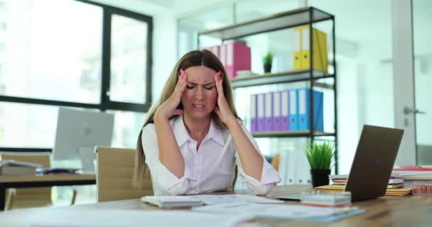 Chronická bolest hlavy a mladá vyčerpaná žena trpící migrénou v práci. Manažer dotýká spánků a zmírňuje bolest - Záběry, video