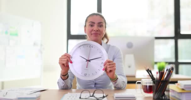 Γυναίκα με ένα μεγάλο στρογγυλό ρολόι τοίχου στο γραφείο. Υπεύθυνος προσωπικού και διαχείριση του χρόνου εργασίας - Πλάνα, βίντεο