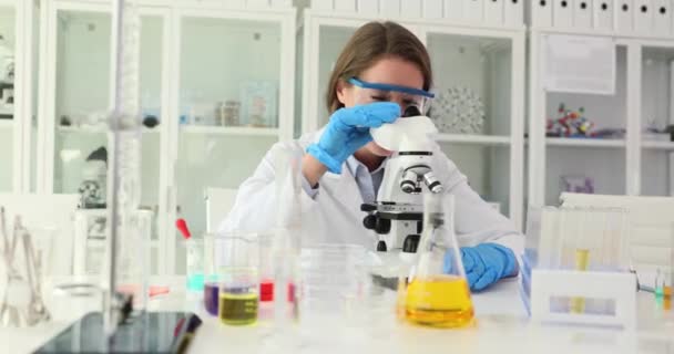 Scientist working in laboratory smiles and waves hand confidently looking at camera. Biologist doctor in medical laboratory - Footage, Video