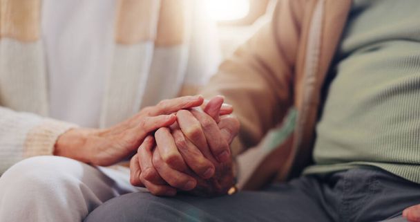 De mãos dadas, empatia e um casal de idosos se fecham em sua casa por amor, apoio ou confiança na aposentadoria. Esperança, cura ou simpatia com pessoas idosas em um sofá na sala de estar de sua casa. - Foto, Imagem