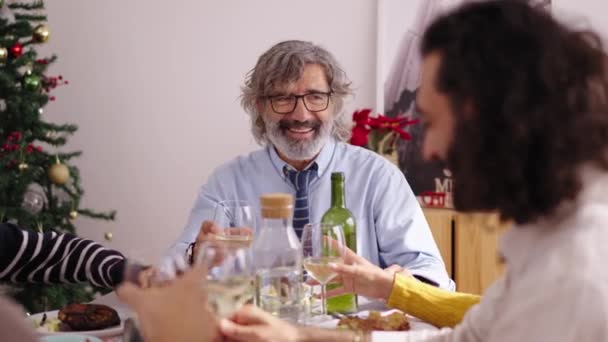 Famiglia caucasica sorridente che festeggia il pasto di Natale insieme brindando con vino bianco a tavola festiva. La gente allegra si è riunita per vacanze invernali. Tre generazioni felici che si godono la vita domestica.  - Filmati, video