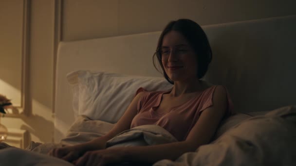 Smiling girl resting bed before sleep. Joyful happy woman dreaming at cozy home. Calm cheerful model holding laptop relaxing in evening. Sleepless female contemplating recalling weekend at night. - Footage, Video