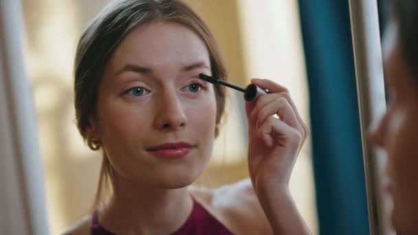 Closeup girl using mascara applying on eyelashes. Woman reflection in mirror doing evening romantic makeup. Attractive relaxed female preparing for date party at home. Beauty routine lifestyle concept - Footage, Video