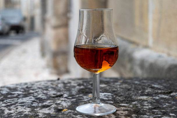Tasting of aged in barrels cognac alcohol drink and view on old streets and houses in town Cognac, Grand Champagne, Charente, strong spirits distillation industry, France - Photo, Image