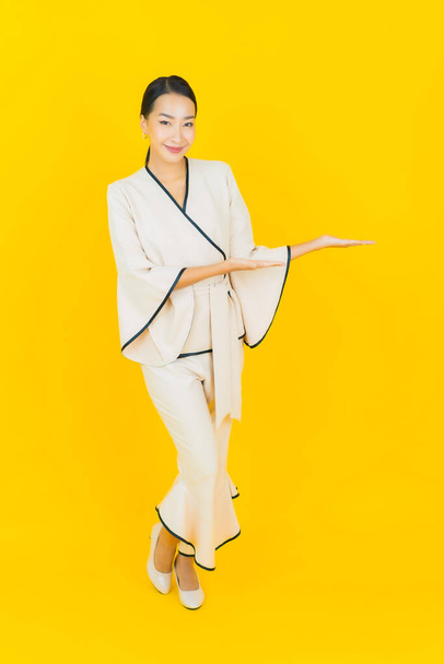 笑顔とアクションと美しい若いビジネスアジアの女性黄色の背景 - 写真・画像