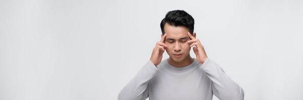 Knappe Aziatische man met hand op hoofd, hoofdpijn door stress. Lijdende migraine. - Foto, afbeelding