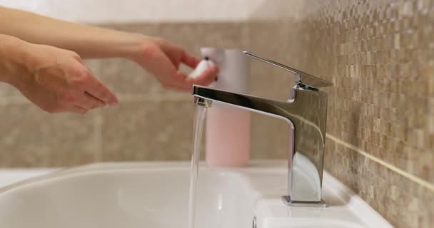 Vrouw wast haar handen grondig met vloeibare zeep in de badkamer thuis of in een hotel. Gezondheidsconcept, zorg voor schone handen. Hoge kwaliteit 4k beeldmateriaal - Video