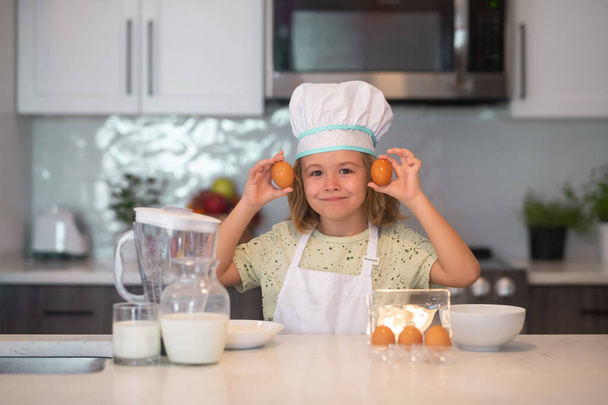 Criança cozinheiro chef com ovos. Chef miúdo a cozinhar na cozinha. Criança cozinheiro chef prepara comida na cozinha. Crianças a cozinhar. Menino adolescente com avental e chapéu de chef preparando uma refeição saudável - Foto, Imagem