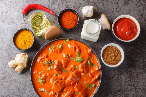Delicious creamy chicken tikka masala surrounded by ingredients close-up in a bowl on the table. Horizontal top view from abov - Photo, Image
