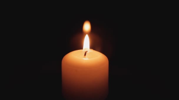 Ένα κερί καίει σε σκοτεινό φόντο. Ένα κερί λάμπει στο σκοτάδι, καίει και μετά από λίγο μια ριπή ανέμου προσπαθεί να σβήσει τη φωτιά. - Πλάνα, βίντεο