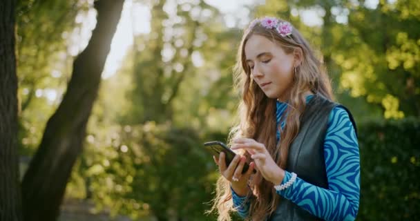 Sarışın genç kadın tatilde bahçede dikilirken cep telefonu kullanıyor. - Video, Çekim