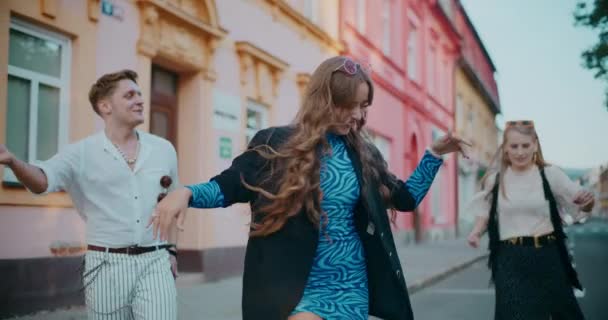 Alegre amigos femeninos y masculinos bailando en la carretera mientras disfruta de vacaciones en la ciudad - Imágenes, Vídeo
