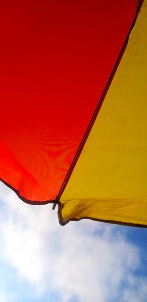 pieces of red and yellow umbrellas on a blue sky background - Photo, Image