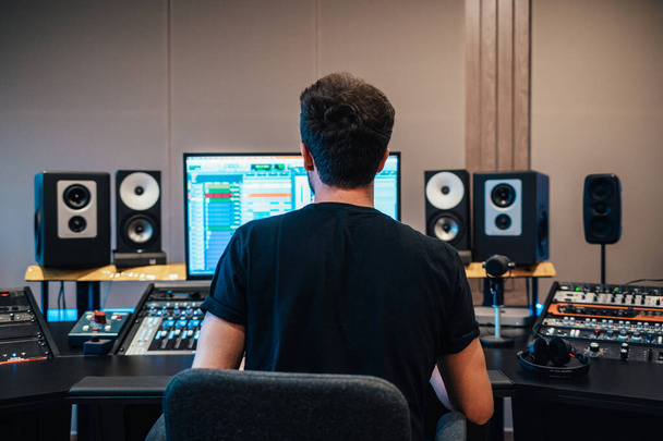 Вид сзади на человека, работающего в студии звукозаписи в одиночку - Фото, изображение