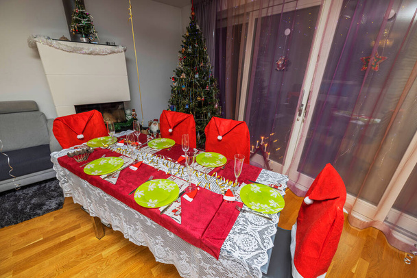 Beautiful view of interior of room with served Christmas table and Christmas tree decorated with New Years toys.  Sweden. - Photo, Image